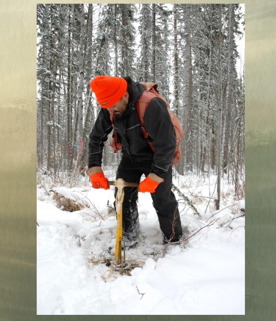 Man standing up to drill a hole in snowy forest