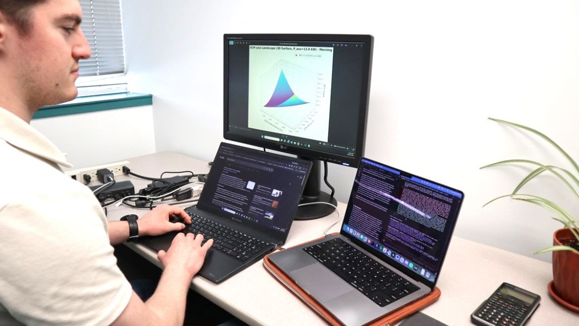 A scientist analyzes data at a computer desk on multiple computer screens.