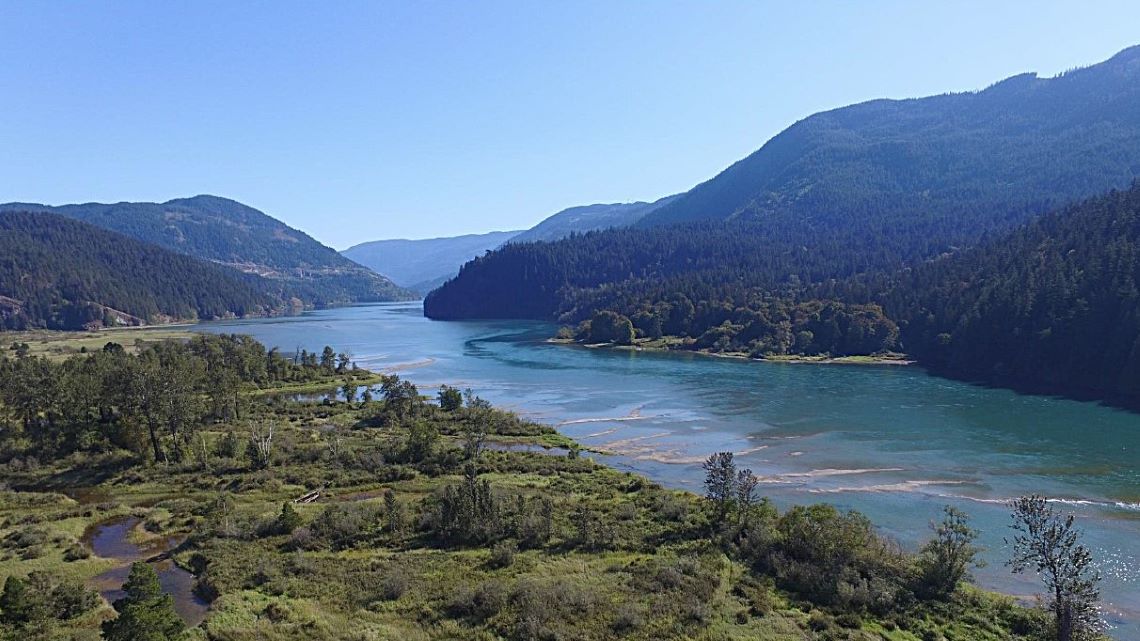 A wide aerial view of the Harrison watershed with shrubs in the foreground and low mountains in the background.