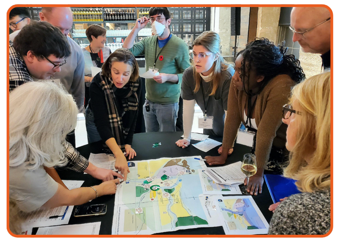 A group of people examining a map around a table.