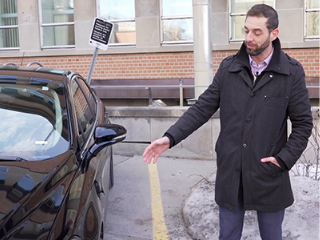 Zero-emission vehicle expert, Yves Madore, standing next to an electric vehicle.