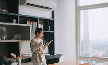 Woman in living room, wall mounted AC unit in background.