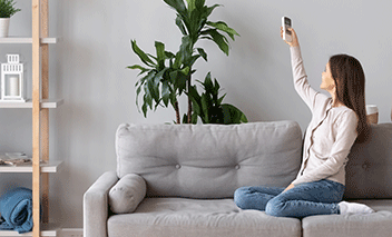 Woman turns on her heat pump heating system or air conditioner.