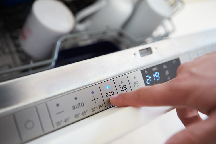 Close up of man selecting economy cycle on dishwasher