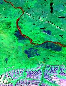 The image has a predominant green component with red tones in the water bodies due to sediment