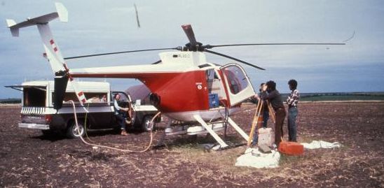 Airplane on the ground with technicians and equipment in a field.