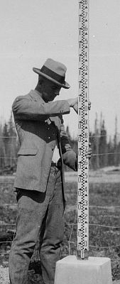 Technician taking a measurement with an Invar rod