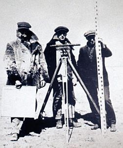 Three technicians holding levelling equipment outside