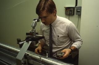 Technician taking a measurement indoors using a rod calibration bench