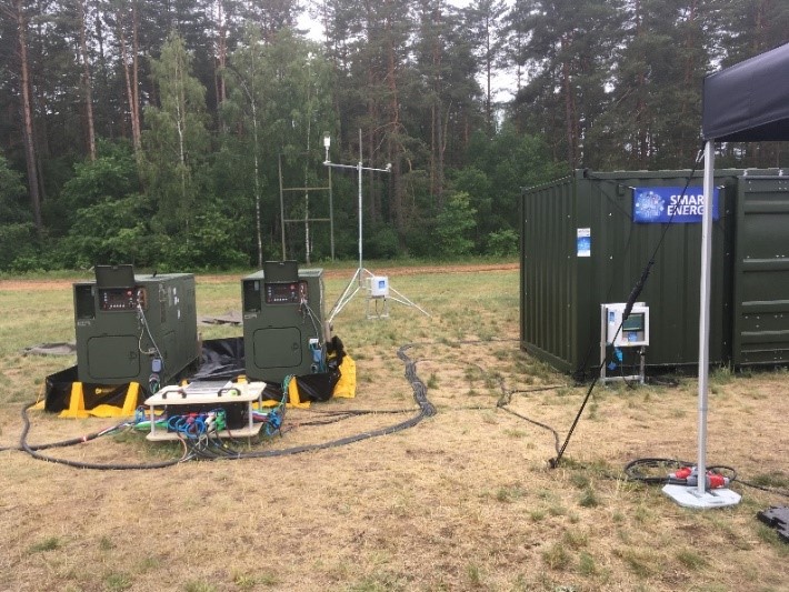 Large metal containers and two smaller metal boxes, with cables and wires, are seen in the middle of a field as part of a monitoring demonstration for the Capable Logistician exercise.