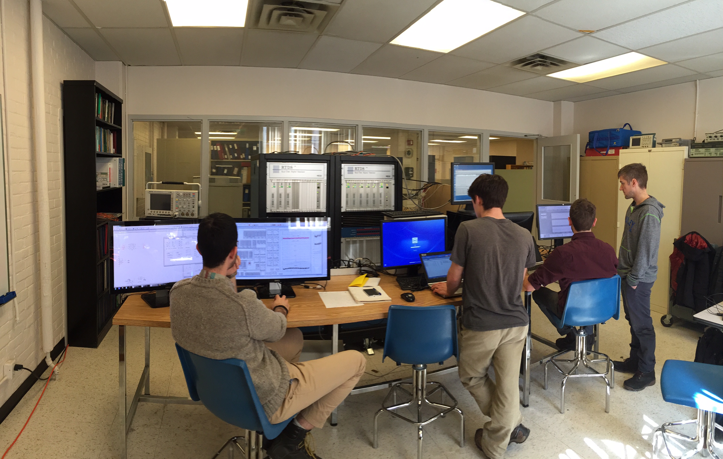 Test facility environment with 4 engineers from Hatch working at computer terminals connected to real time simulator and microgrid controls hardware