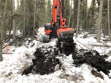 An excavator is used to create elevated mounds to improve planting conditions.