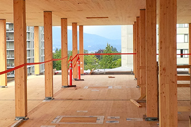 An unfinished hallway without windows or walls, but with wooden ceilings, beams and floors made from cross-laminated timber.