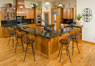 A large kitchen with hardwood flooring and cabinets. The fridge, stove fan and kitchen island also have hardwood paneling. (iStock.com/chandlerphoto)