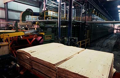 Three stacks of plywood on a platform in a mill