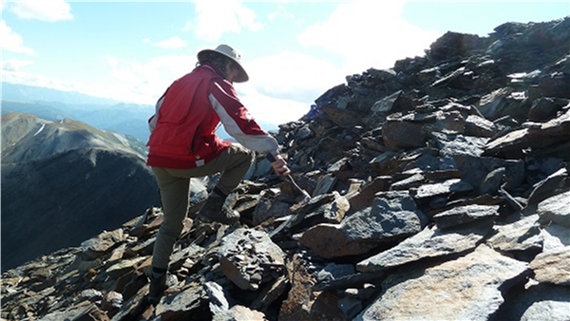 A photo of a geologist exploring a rocky surface to identify potential areas for ore deposits.