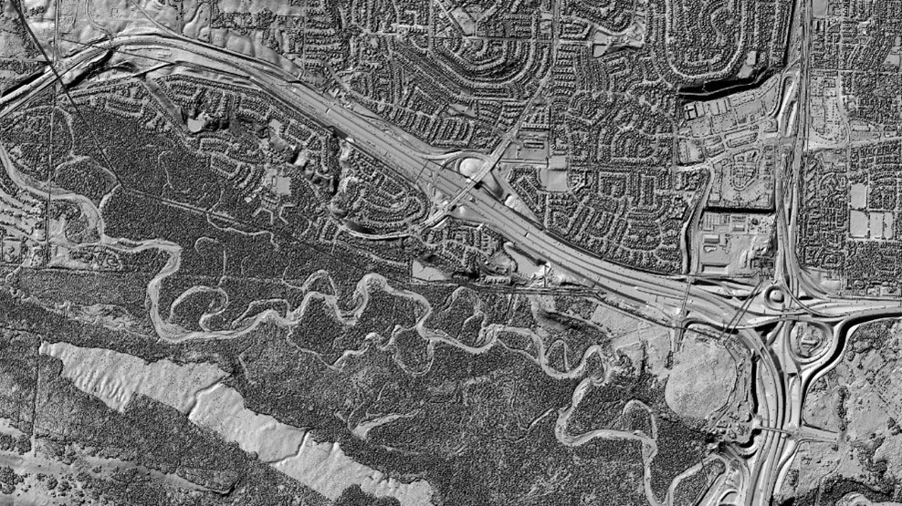 Black and white 3D reliefs of the surface of the ground including roads, water, terrain, trees and buildings.