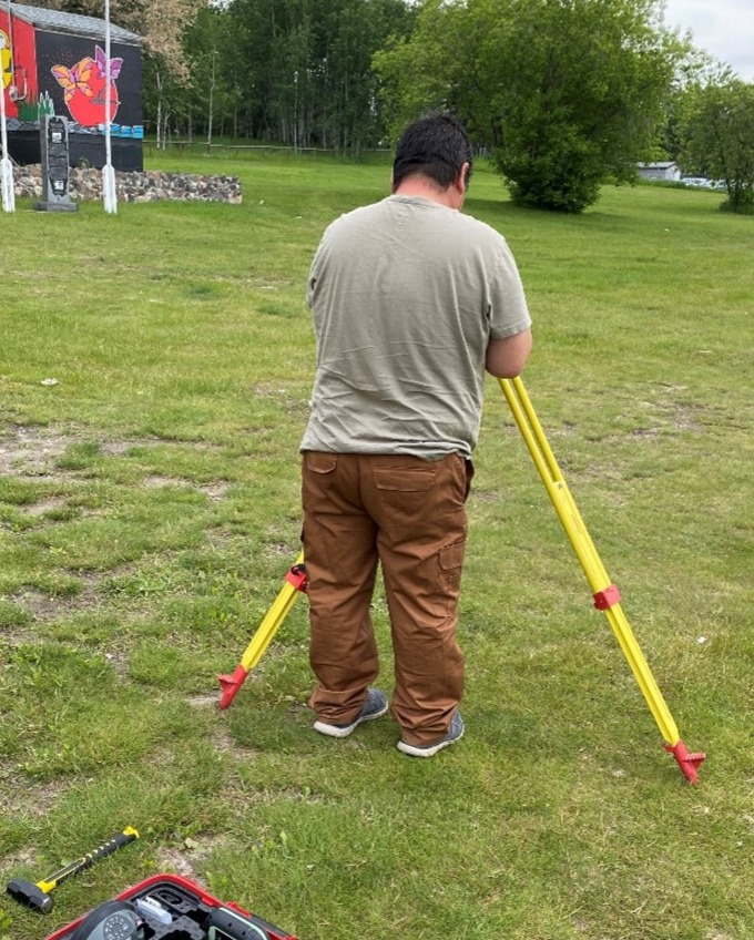 A person standing in a field with surveying equipment