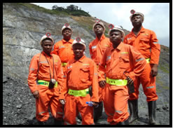Six men with orange mining gear and hard hats