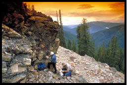 Three geologists on the side of a mountain collecting rock samples