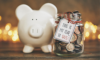 Piggy bank beside a jar of coins that says “This is my year to save”.