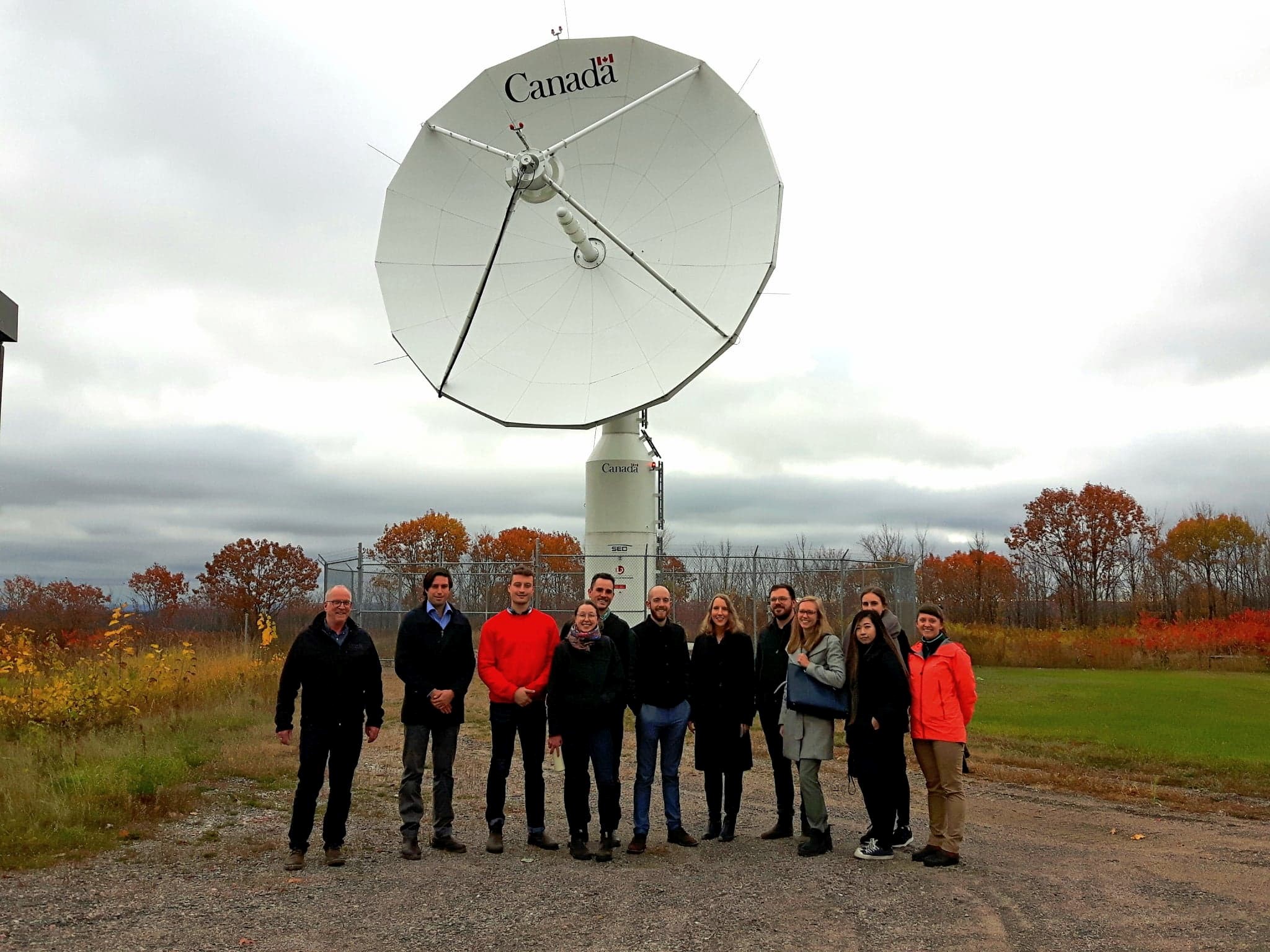 People standing in front of a satellite dish