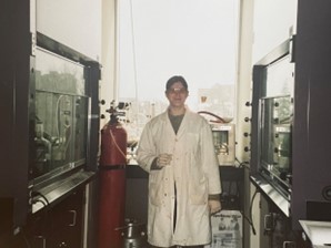 Woman in white lab coat surrounded by equipment in a scientific lab.