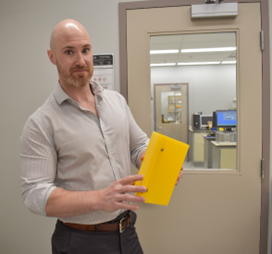 Scientist in lab holding a book-size insect trap. 
