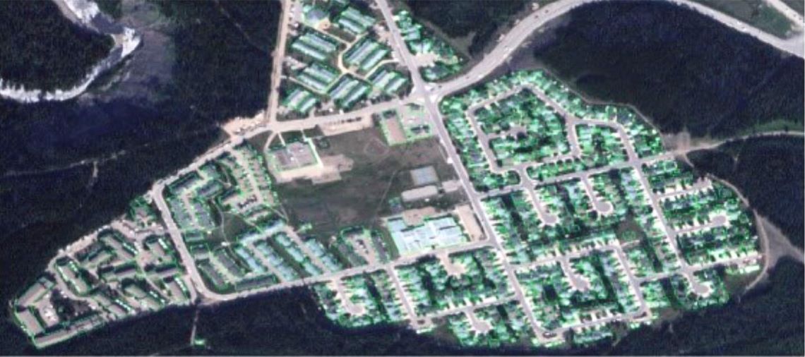 Aerial view highlighting the buildings of a suburban community surrounded by forest.