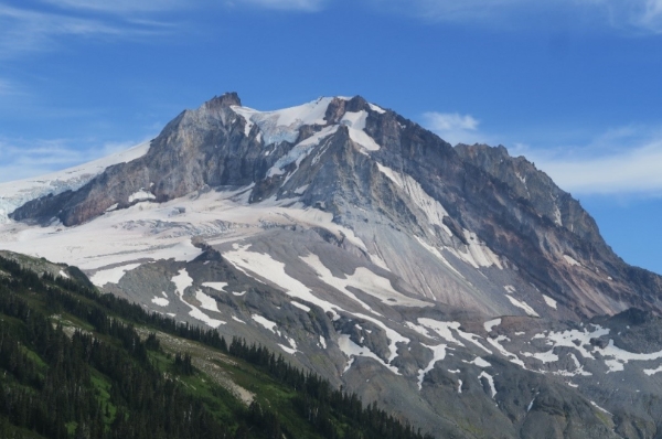 A scenic view of a rugged mountain peak covered with patches of snow under a clear blue sky.