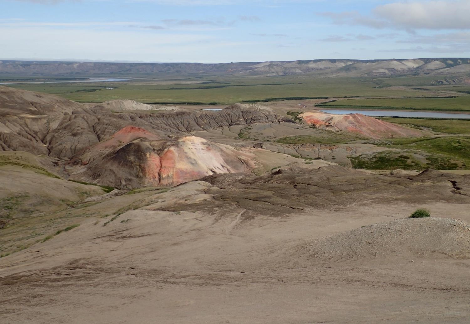 Landscape of gentle hills showing layers of red and yellow shales.