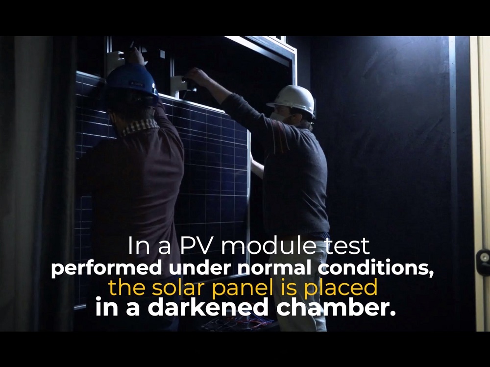 Inside darkened chamber two men place solar panel on testing dock. On screen text: In a PV module test performed under normal conditions the solar panel is placed in a darkened chamber.